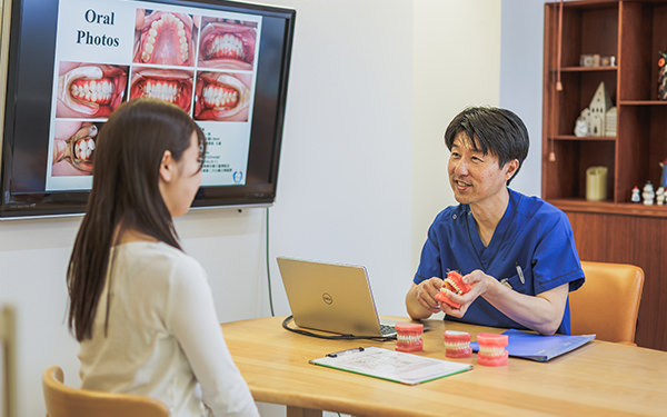 院長が患者さんと向かい合い、歯並びの状態を説明しているカウンセリングの様子